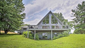 Uma casa moderna com um deck espaçoso, rodeada por vegetação exuberante e árvores.