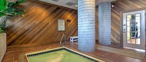 A spa area with a wooden wall, a stone pillar, a bench, and a tiled floor.
