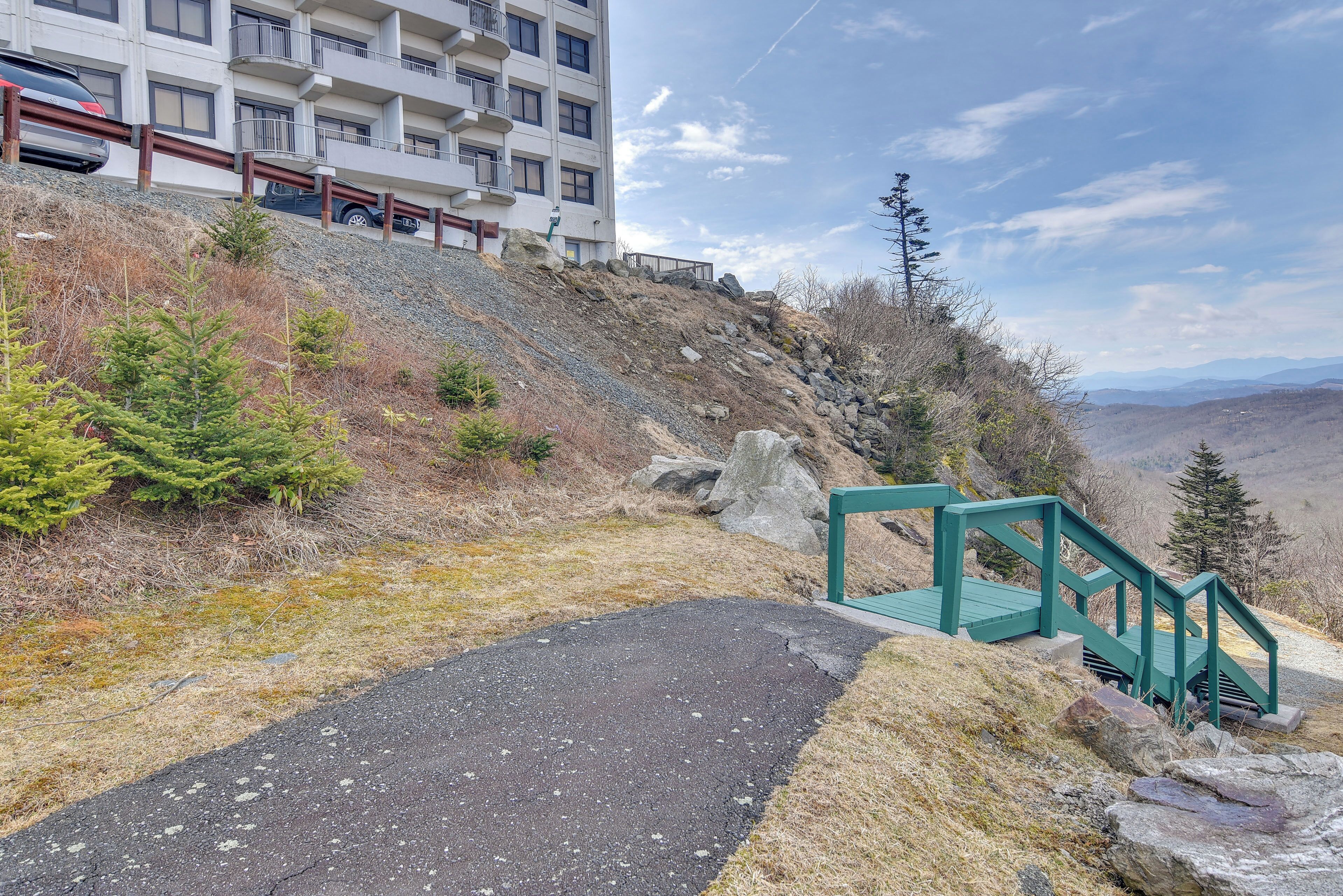 Un vialetto lastricato che conduce a una scalinata verde, con un edificio sullo sfondo.