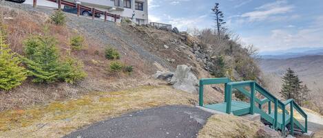 A paved path leading to a green staircase with a building in the background.
