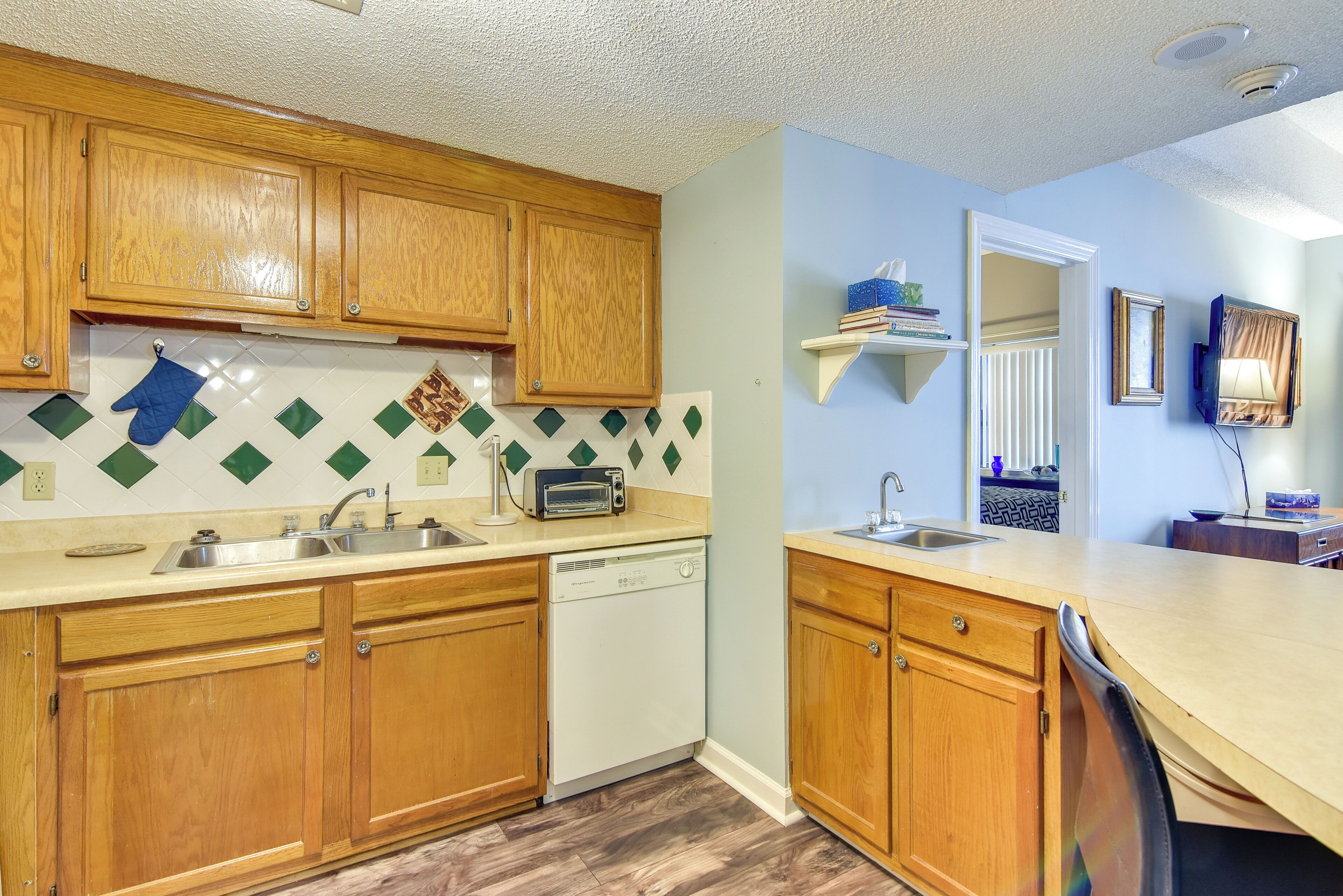 A kitchen with wooden cabinets, a dishwasher, a toaster, and a tiled backsplash.