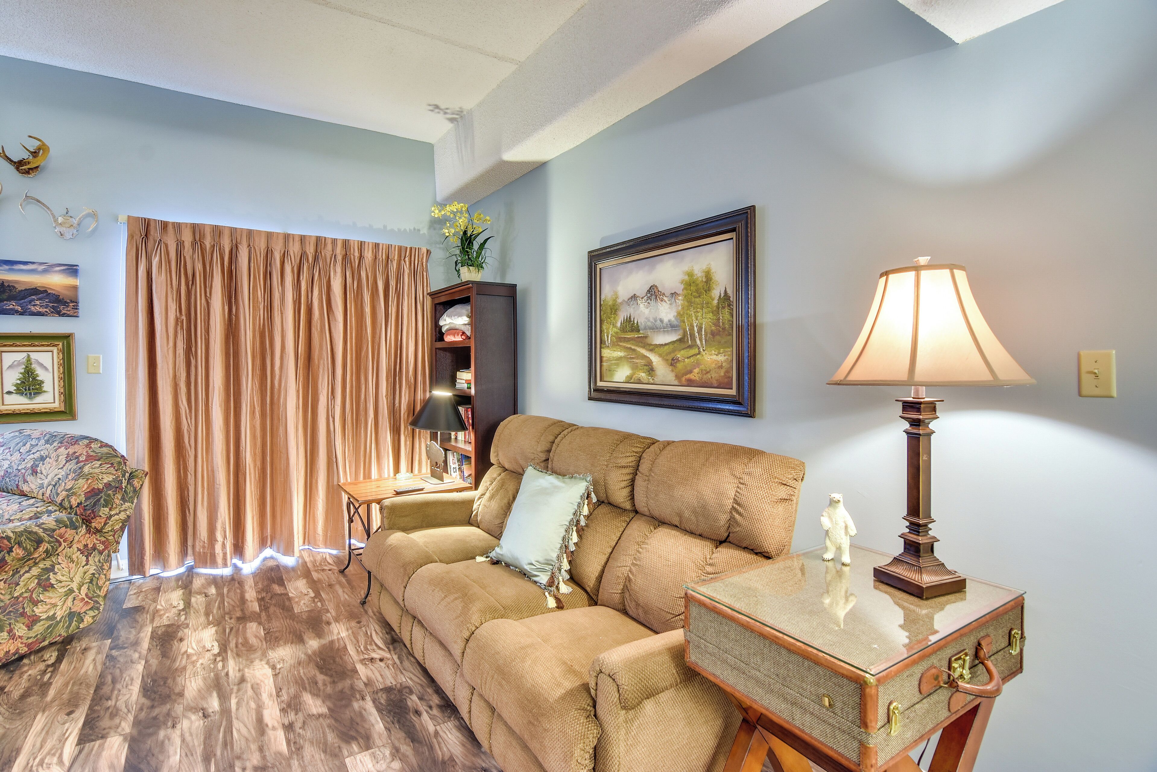 A living room with a sofa, a lamp, a painting, and a curtain.
