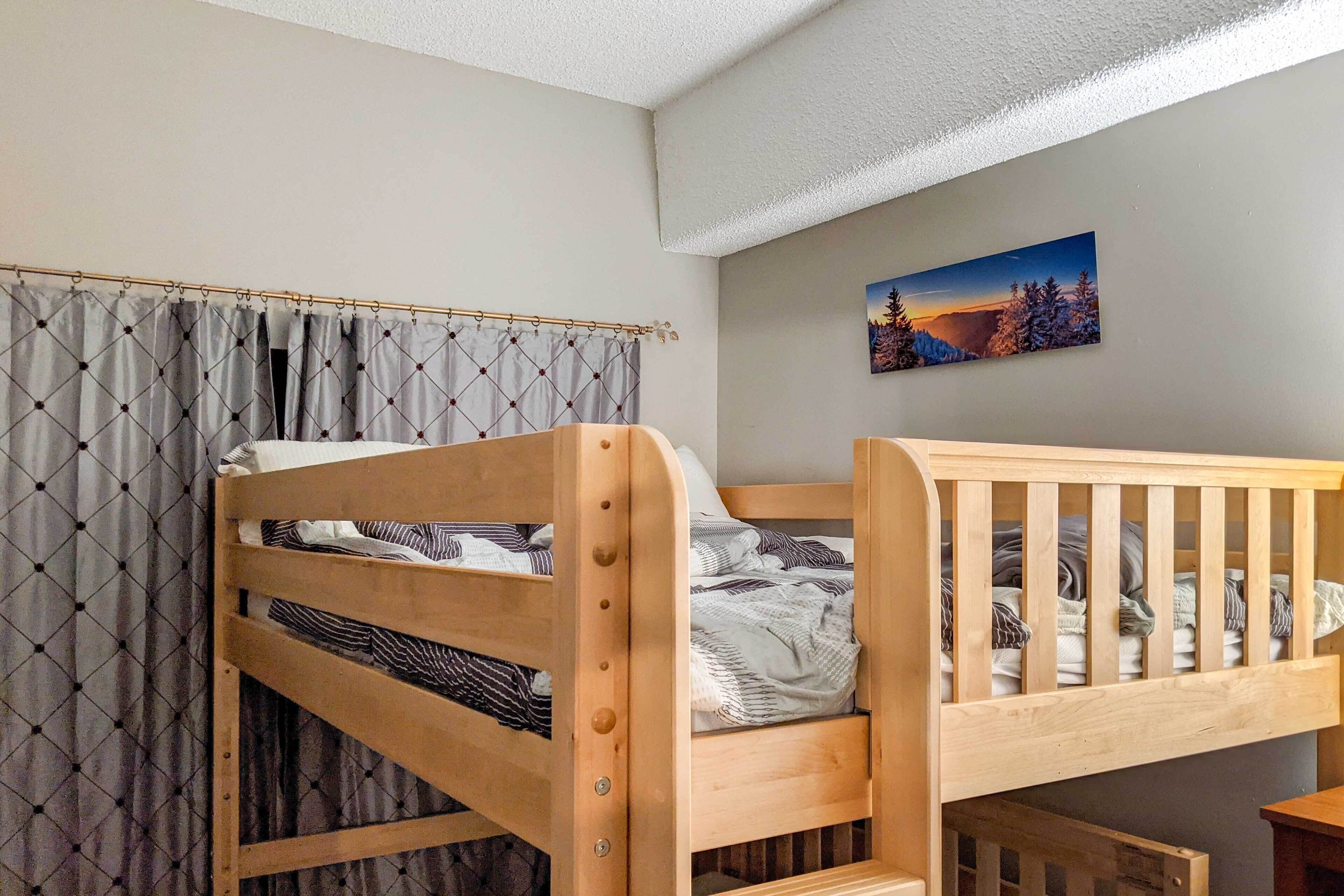 Een kamer met een stapelbed, een gordijn en een schilderij aan de muur.
