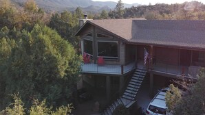 A two-story house with a balcony, a staircase, and a view of mountains.
