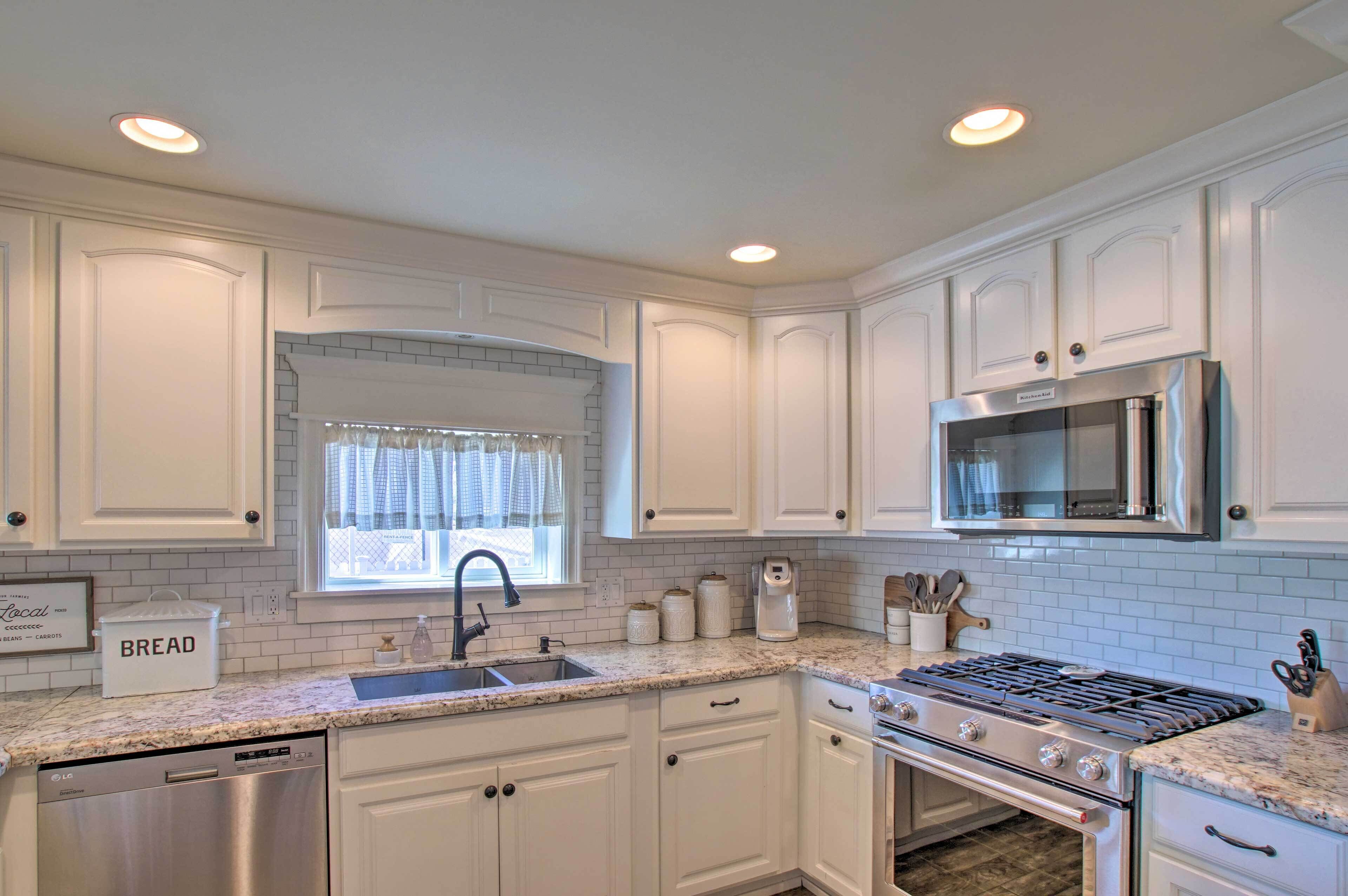 Una cocina moderna con armarios blancos, estufa de acero inoxidable y microondas integrado.