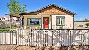 A single-story house with a red door, a covered porch, and a white picket fence.