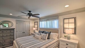 A bedroom with a bed, dresser, nightstands, and a ceiling fan.