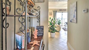 A hallway with a decorative metal gate, a sign that says "LET THE SEA GET YOU FREE," and a potted plant. - Ormond Beach Condo w/ Balcony & Views (Ormond Beach)