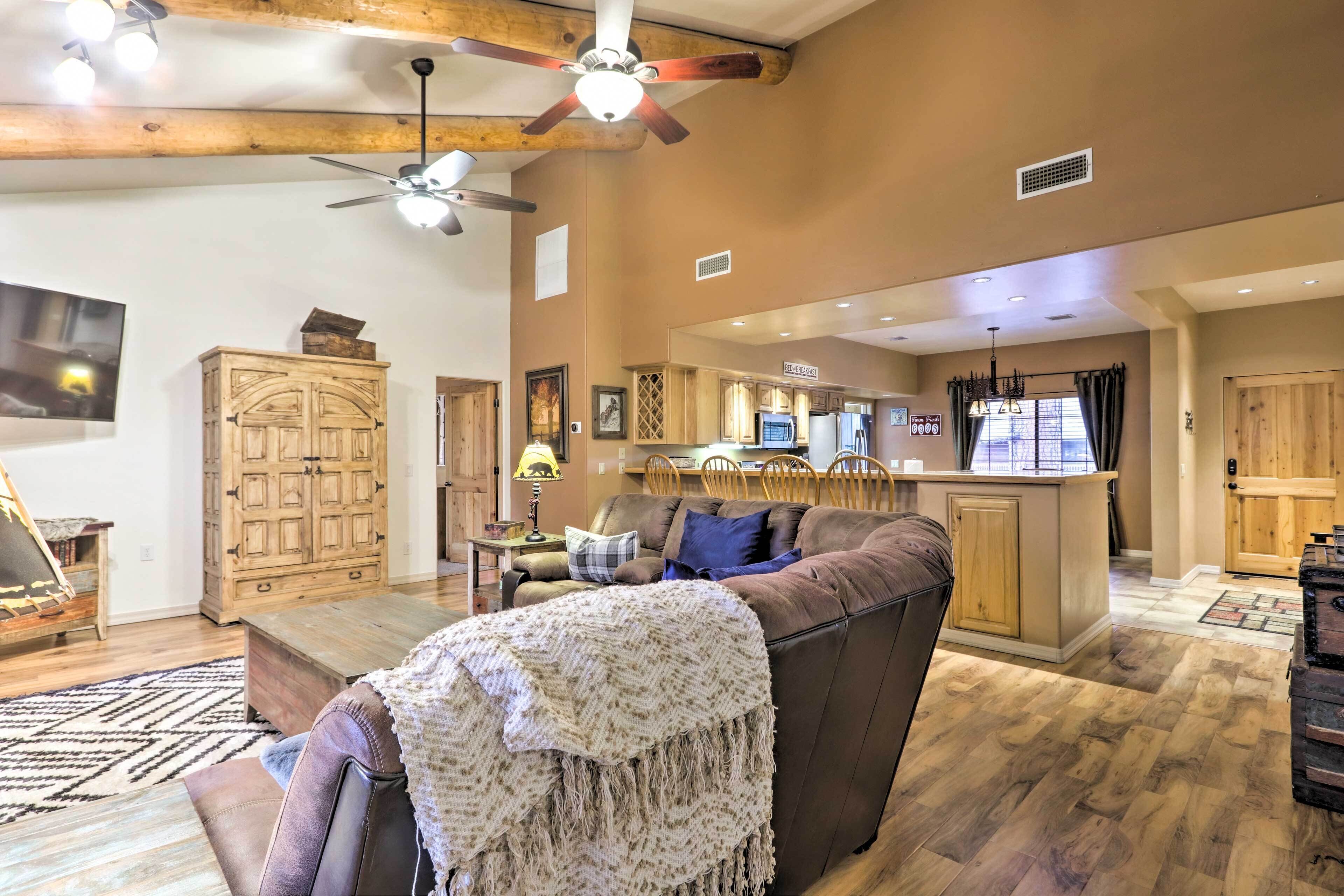 A spacious living area with a brown leather couch, wooden cabinets, and a kitchen in the background.