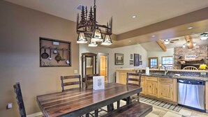 A spacious kitchen with a wooden dining table, built-in cabinets, and a stone accent wall. - Pinetop Escape: Charming Mountain Condo w/ Balcony (Pinetop)