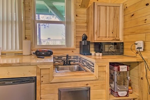 Una cocina de madera con un lavaplatos integrado, una cafetera, un microondas y un lavavajillas Frigidaire.