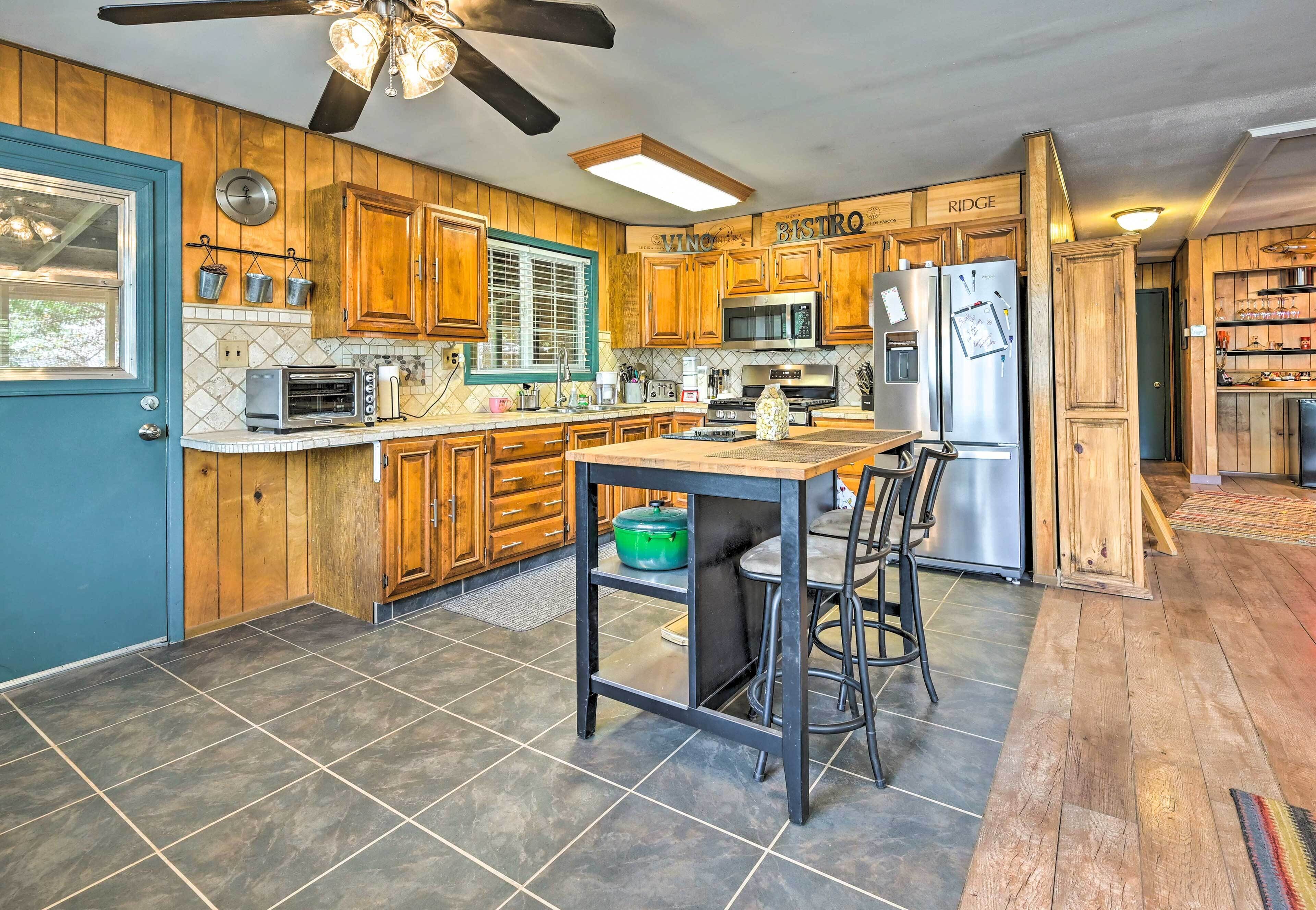 A kitchen with wooden cabinets, a microwave, a refrigerator, a sink, and a dining area with a table and chairs.