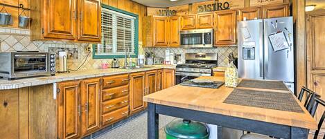 A kitchen with wooden cabinets, a stainless steel refrigerator, a microwave, and a stove.