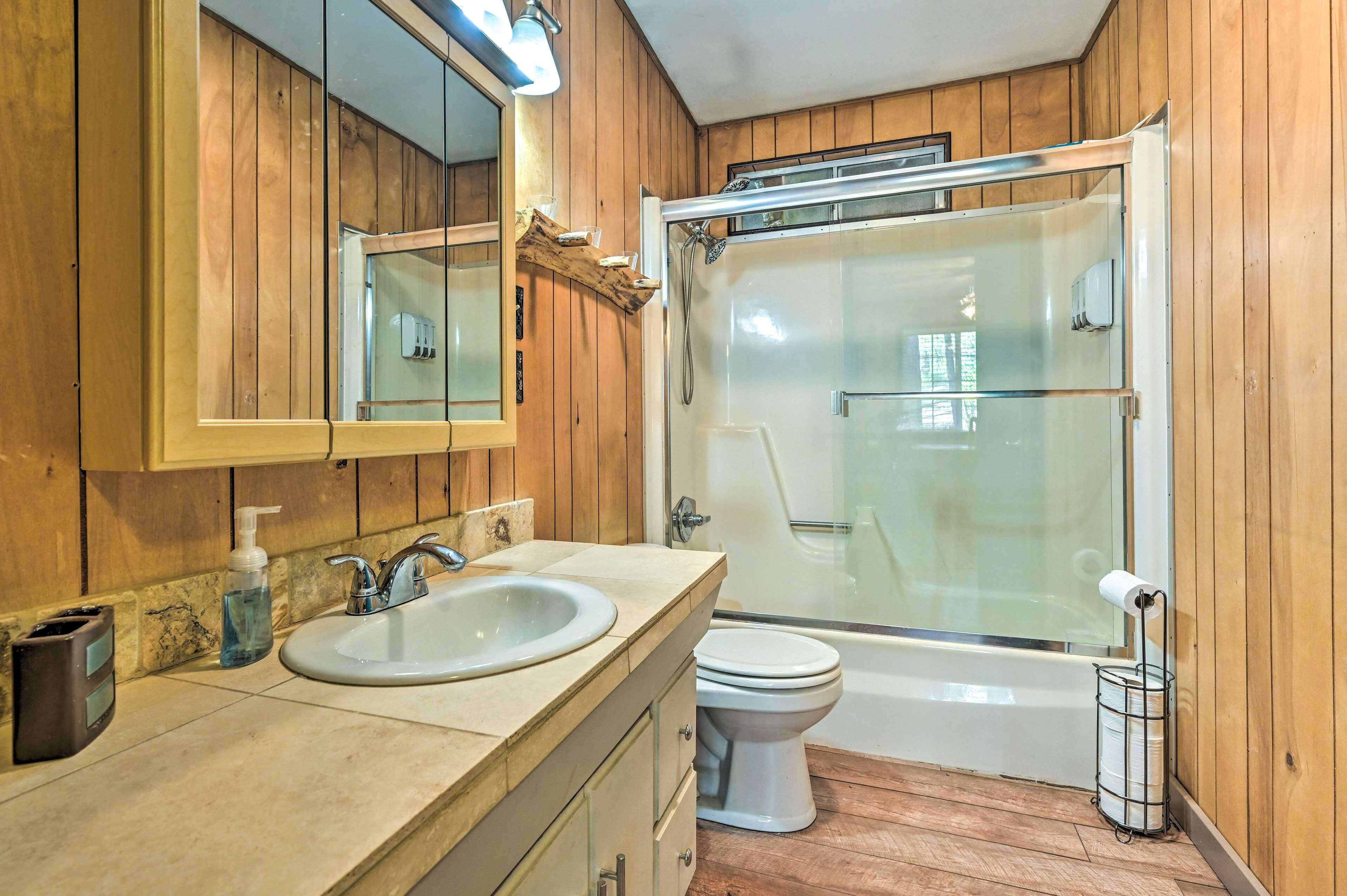 Een badkamer met houten lambrisering, een wastafel, een toilet en een douchecabine.