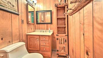 A wooden bathroom with a toilet, sink, and mirror.