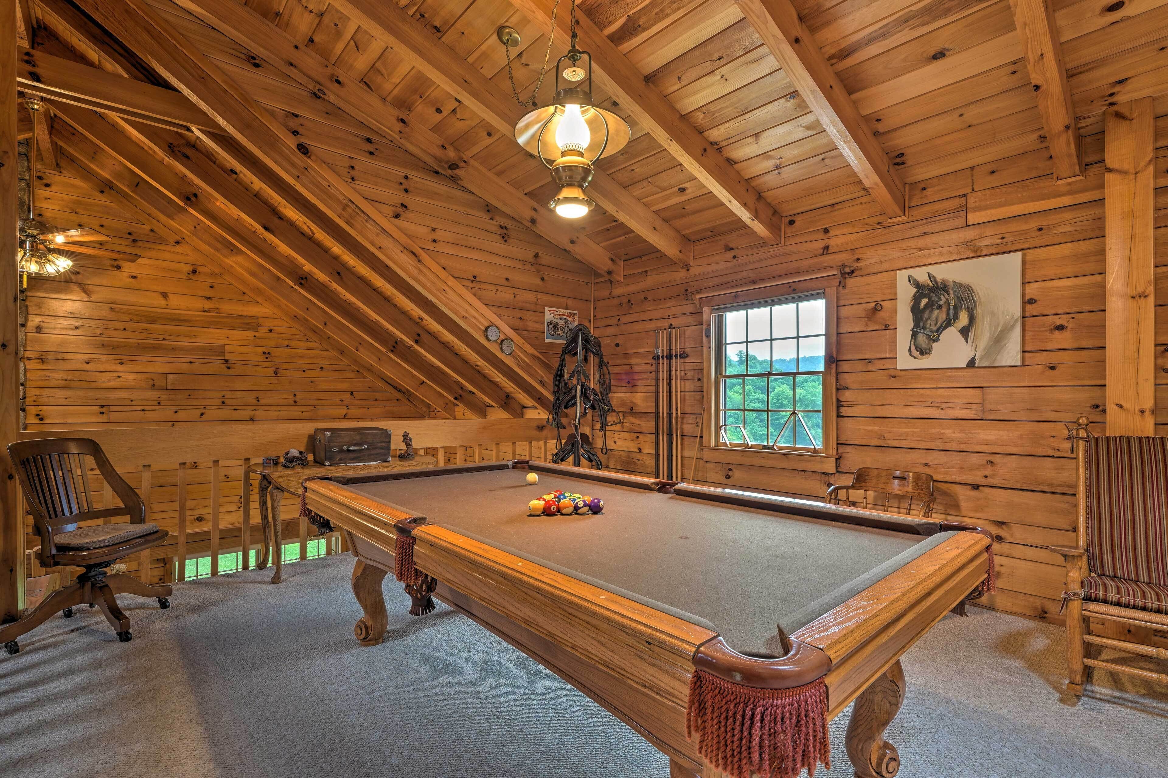 A wooden-paneled room with a pool table, a mounted horse painting, and a window with a view of greenery.