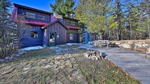 A log cabin with a metal roof, a stone wall, and a wooden deck. - Log Cabin in Wilmington w/ New Hot Tub By Skiing! (Wilmington)