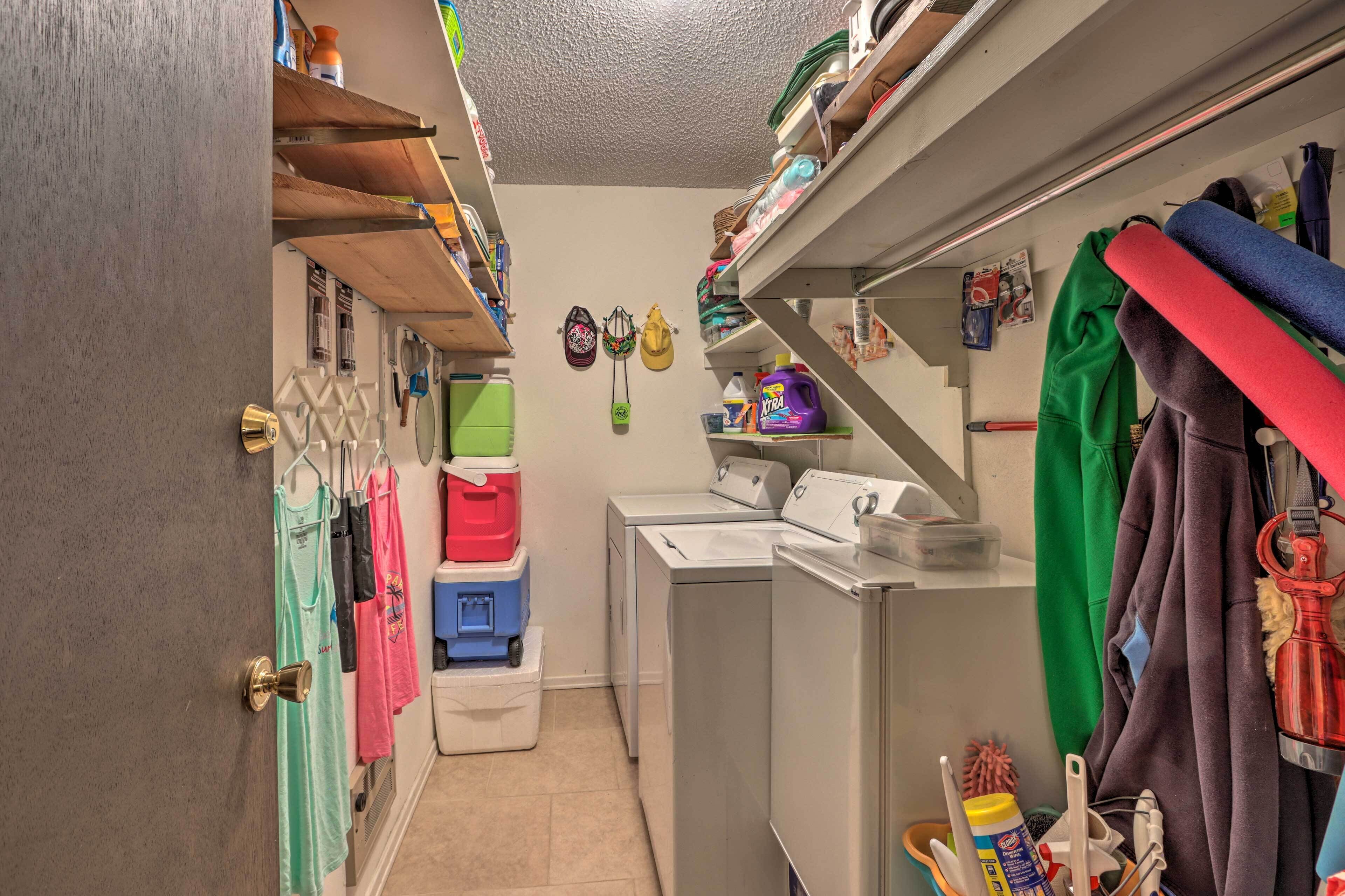 A laundry room with stacked laundry baskets, a washing machine, and various cleaning supplies.
