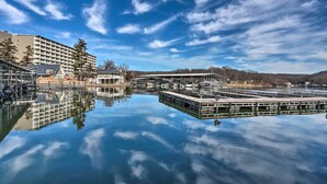 A waterfront hotel with a reflective pool, a dock, and a large building with multiple balconies. - < 1 Mi to Lake! Osage Beach Home w/ Furnished Deck (Osage Beach)
