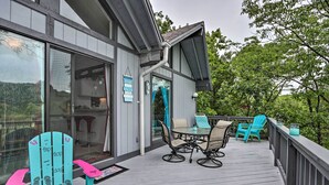 A wooden deck with outdoor furniture, including chairs and a table, and a glass door leading to a kitchen area. - < 1 Mi to Lake! Osage Beach Home w/ Furnished Deck (Osage Beach)