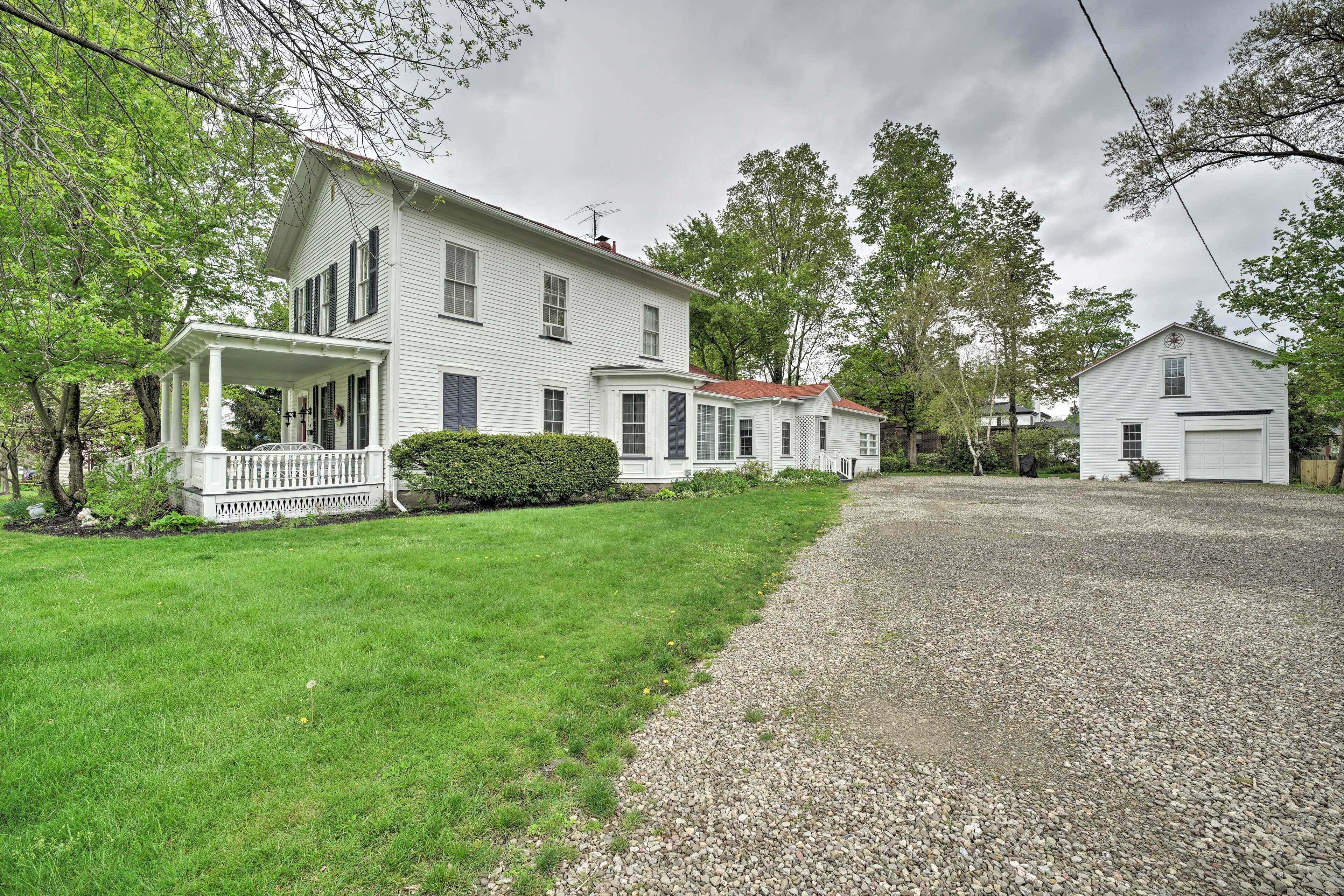 A two-story white house with a covered porch and a gravel driveway.