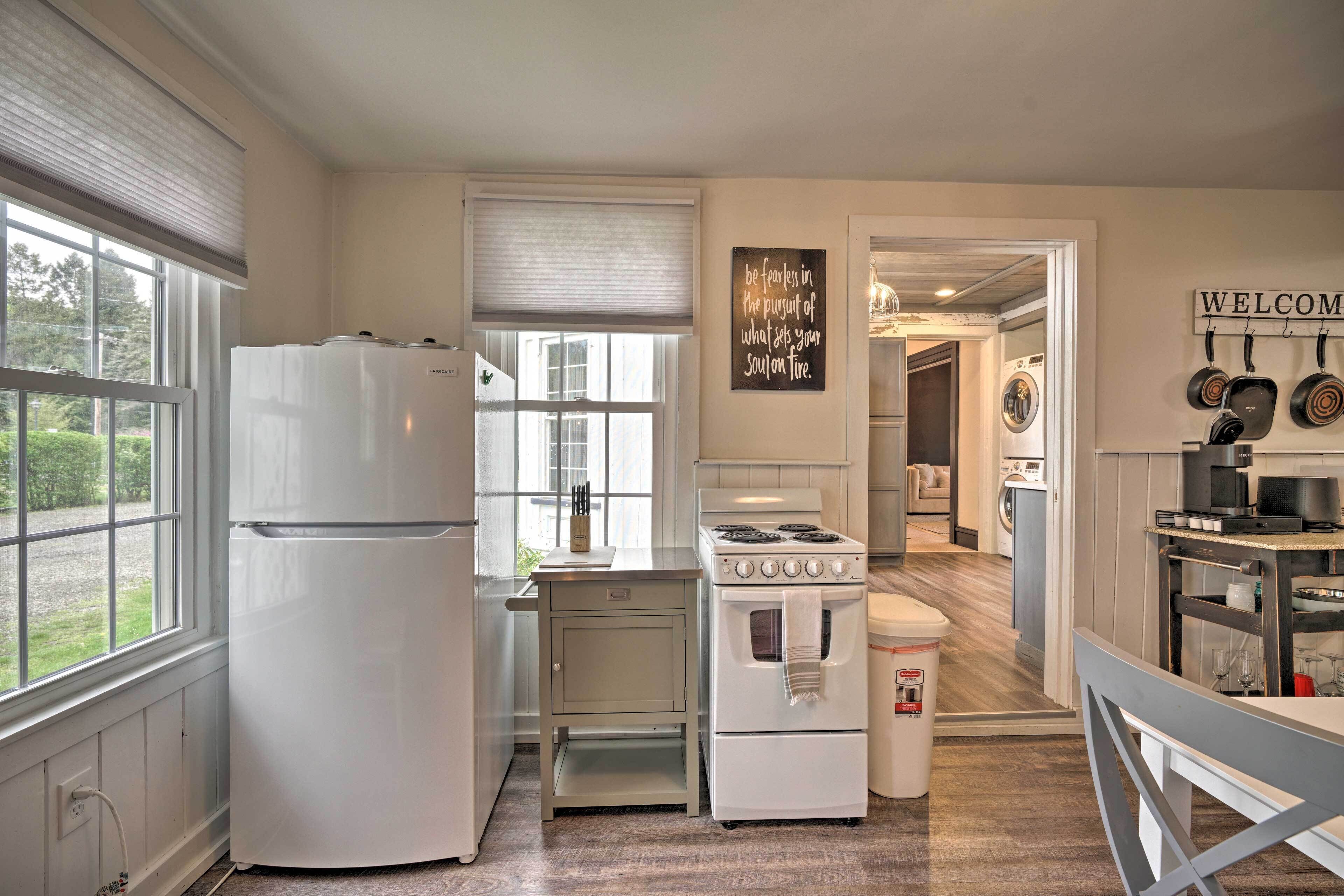 A kitchen with a refrigerator, stove, and a 'WELCOME' sign on the wall.