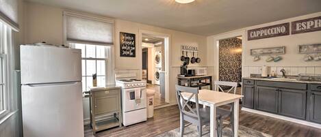A kitchen with a refrigerator, stove, sink, and a dining area with a table and chairs.