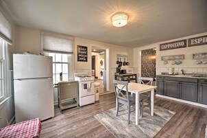Una cocina con refrigerador, estufa, lavamanos y un comedor con mesa y sillas.