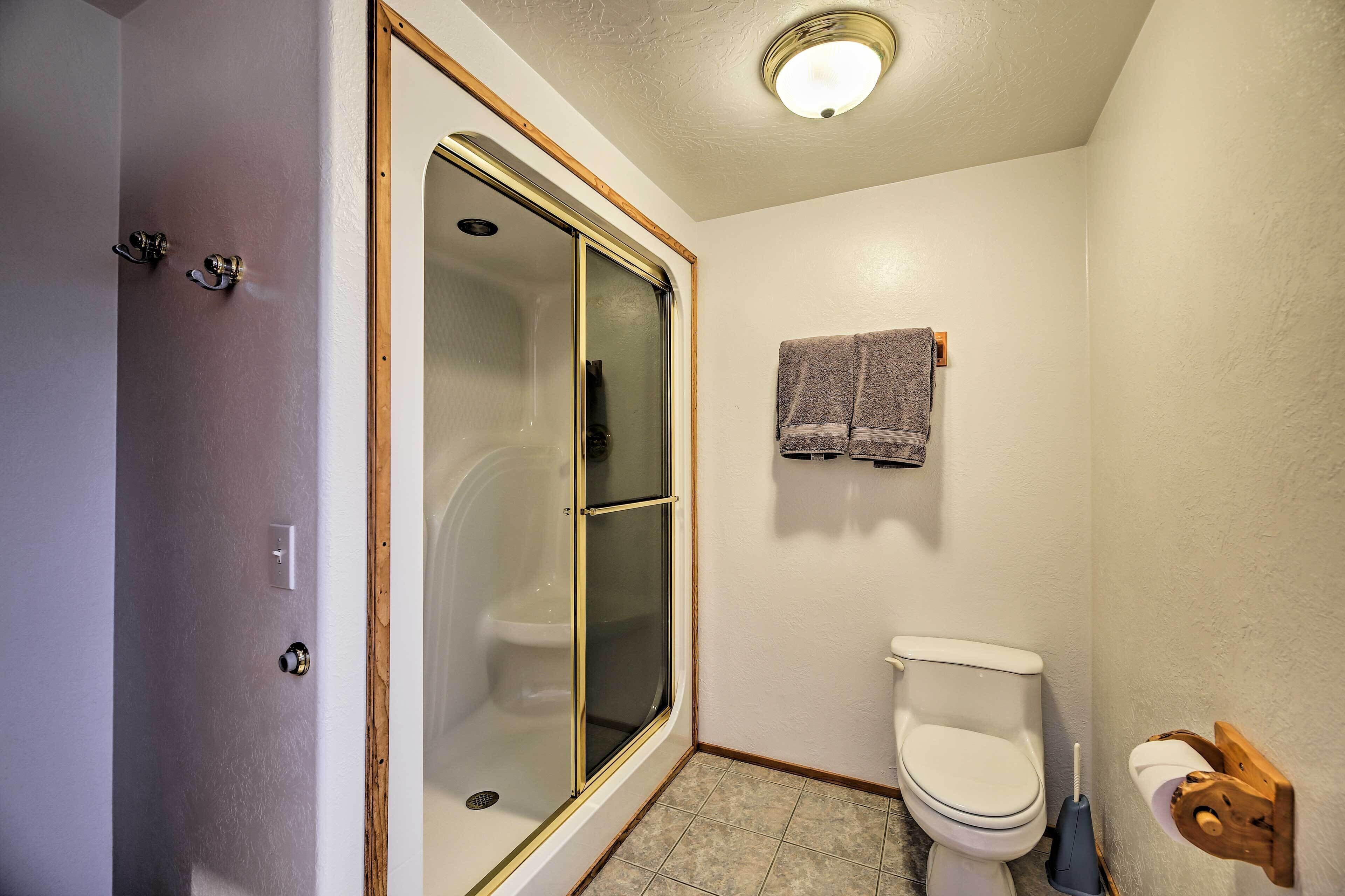 Un baño con ducha de vidrio, inodoro y perchero para toallas.