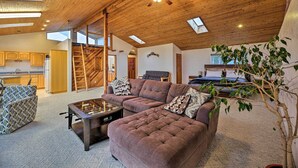 A spacious living area with a high ceiling, wooden beams, and a foosball table. - Sanderling Sea Cottages, Unit A: Pet Friendly! (Waldport)