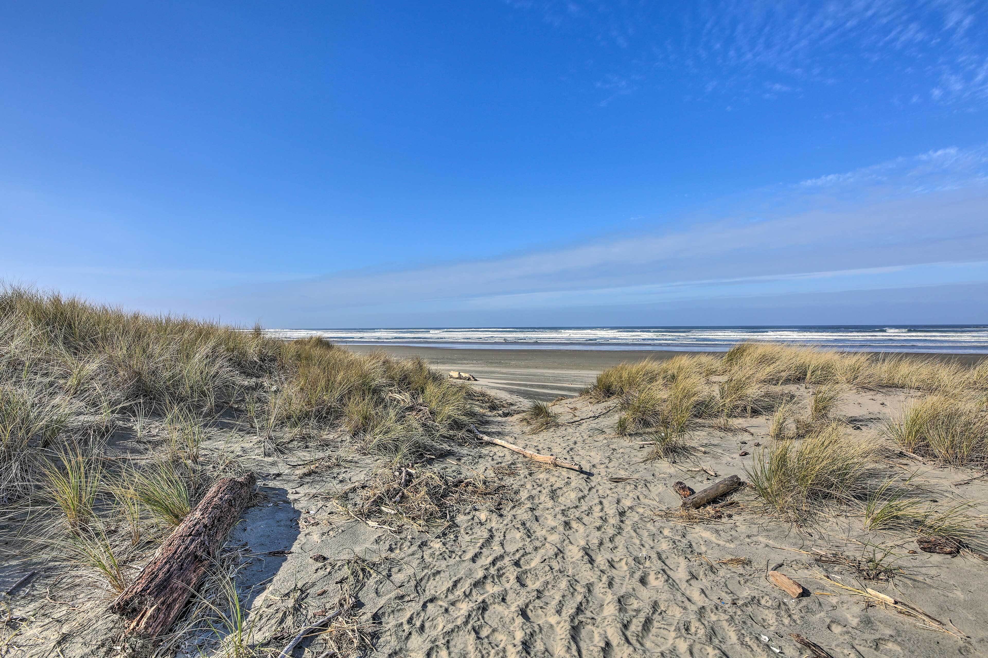 A sandy beach with dunes and a clear view of the ocean.