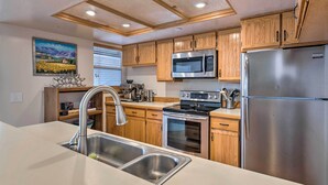 A modern kitchen with wooden cabinets, stainless steel appliances, and a large island with a sink. - 2 Mi to Park City Mtn: Townhome w/ Balcony (Park City)