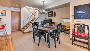 A dining area with a round table and chairs, a chandelier, and a staircase leading to another level. - 2 Mi to Park City Mtn: Townhome w/ Balcony (Park City)