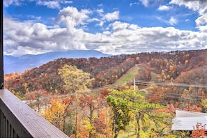 A mountainous landscape with autumn foliage, a wooden deck, and a distant road.