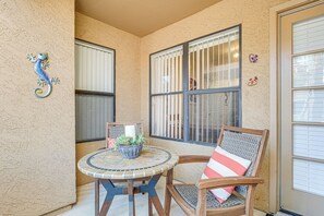 A patio area with a round table, two chairs, and a decorative wall piece. - Near Hiking & Golfing: Scottsdale Resort Condo! (Scottsdale)