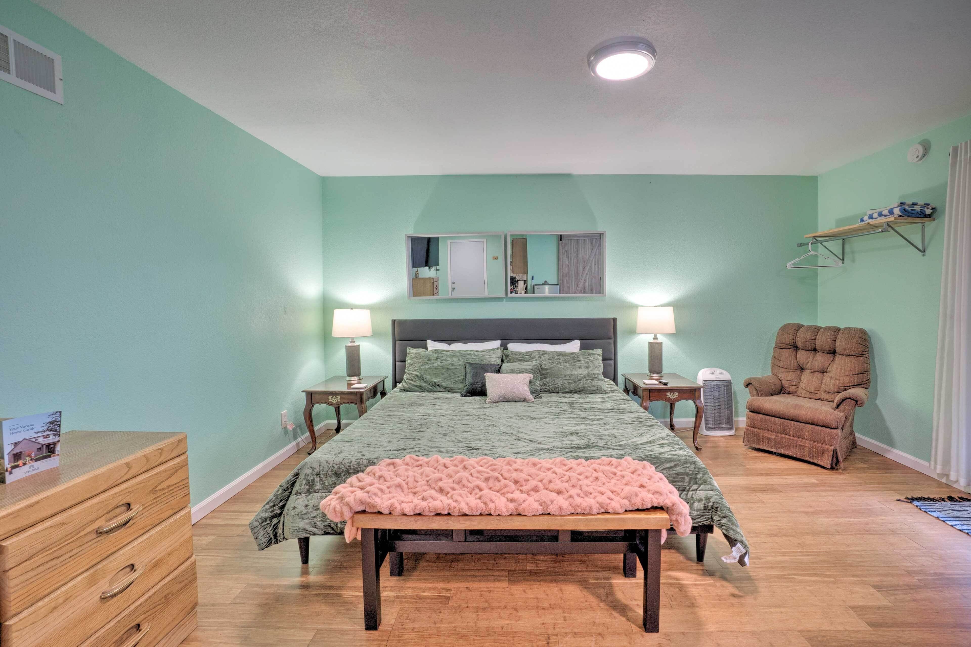 A bedroom with a bed, bedside tables, a chair, a dresser, and a mirror.