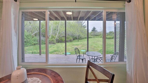 A room with a large window overlooking a deck with outdoor furniture. - Soothing Studio w/ Lush Views: 2 Mi to Beach! (Smith River)