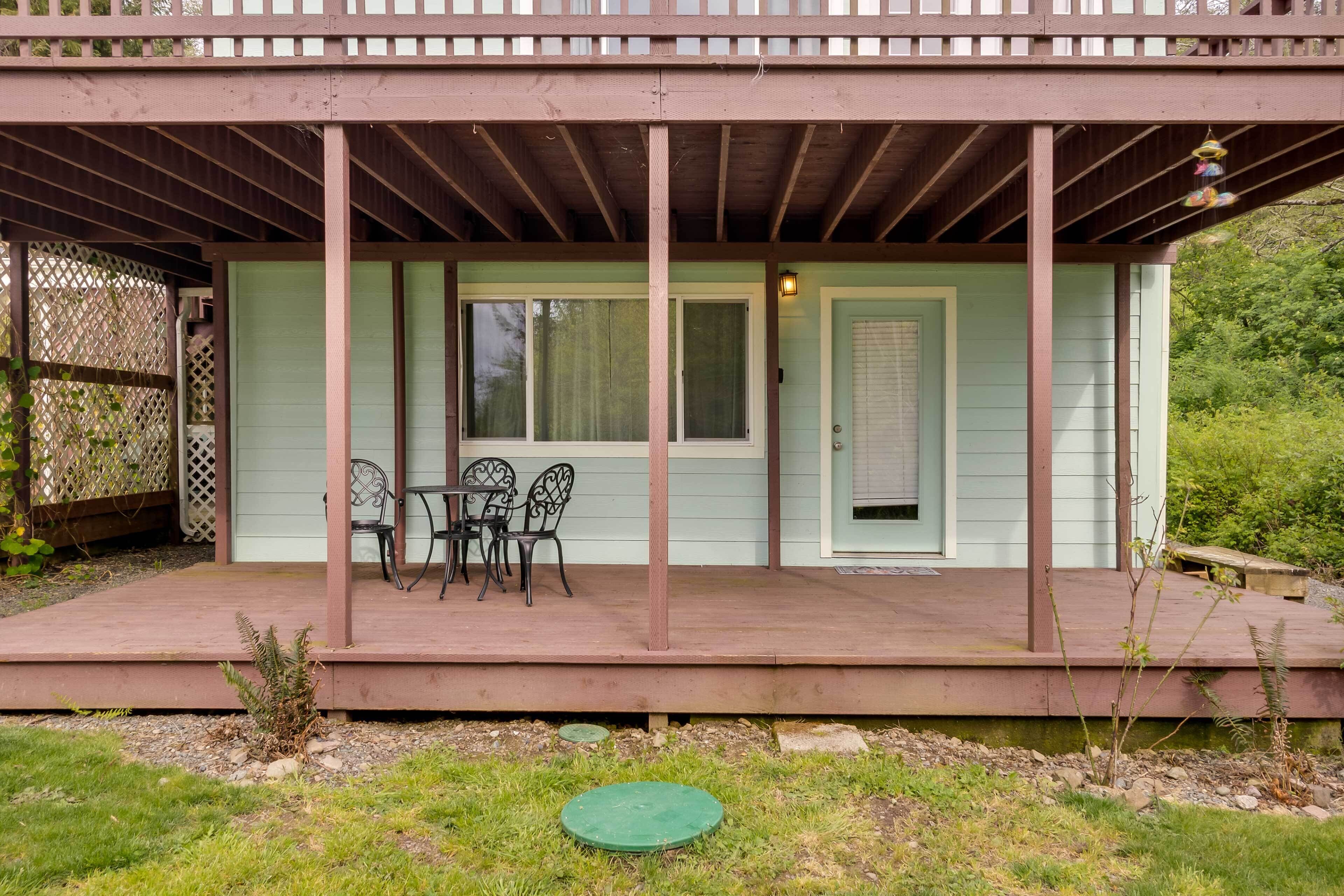 A covered patio with a table and chairs, a door, and a window.