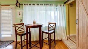 A dining area with a round table and two chairs, a door with a window, and a sign indicating a bathroom. - Soothing Studio w/ Lush Views: 2 Mi to Beach! (Smith River)
