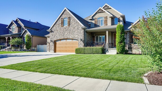 A two-story house with a stone facade, a large garage, and a well-maintained lawn. - Great Salt Lake House: 5,000 Sq Ft, Mtn Views! (Kaysville)