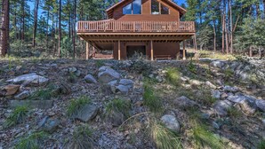 A wooden cabin with a balcony, surrounded by a forest and rocky terrain. - Fish, Hike & Explore: Prescott Cabin w/ Grill! (Prescott)