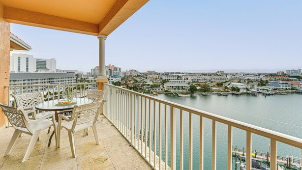 Un balcon avec une table et des chaises donnant sur une marina et sur le paysage urbain.