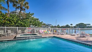 Une piscine avec des chaises longues et des palmiers.