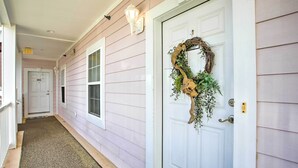 A hallway with a white door, a wreath, and a light fixture. - Little River Condo w/ Pool < 6 Mi to Beach! (Little River)