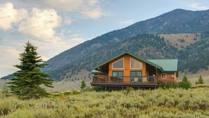 A log cabin with a balcony, surrounded by a mountainous landscape. - Cozy Henrys Lake Escape - 20 Miles to Yellowstone! (Island Park)