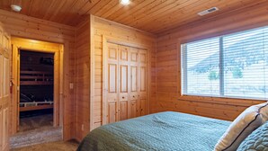 A wooden cabin bedroom with a bed, a closet, and a window with blinds. - Cozy Henrys Lake Escape - 20 Miles to Yellowstone! (Island Park)