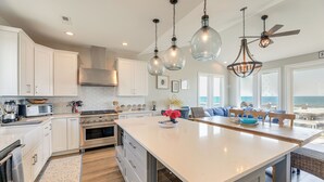 A modern kitchen with white cabinets, stainless steel appliances, and a large island. - Beachfront Oasis w/ 2 Large Decks, BBQ & Views! (Holly Ridge)