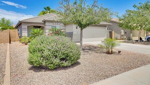 A residential house with a garage, a small garden with a tree and shrubs, and a clear blue sky. - Private Pool & Patio: Home in Surprise! (Surprise)
