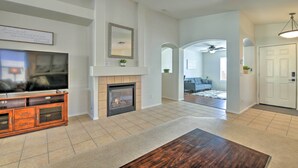 A spacious living room with a fireplace, a television, and a dining area. - Private Pool & Patio: Home in Surprise! (Surprise)