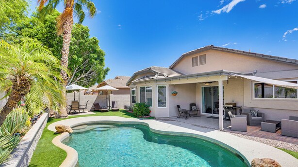 A backyard with a swimming pool, patio furniture, and a covered seating area. - Private Pool & Patio: Home in Surprise! (Surprise)